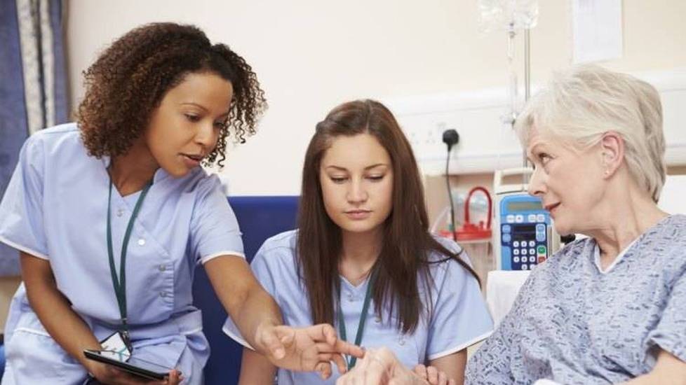 Nurse  teaching new nurse how to provide healthcare to elderly patient in hospital
