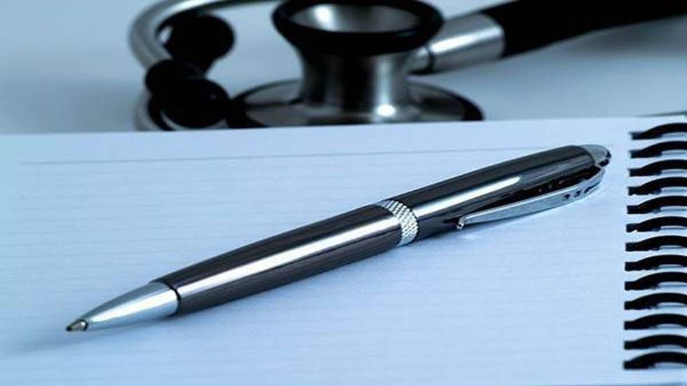 Pen resting on notepad with stethoscope nearby