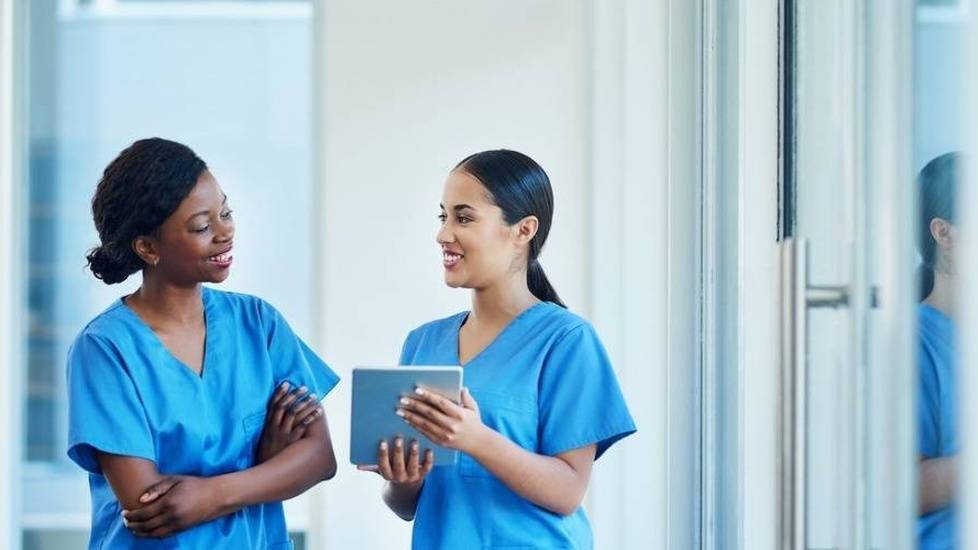 Two nurses in blue scrubs looking over charts
