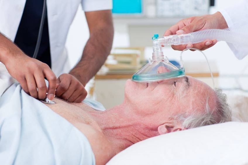 Elderly patient with oxygen and doctor checking heartbeat