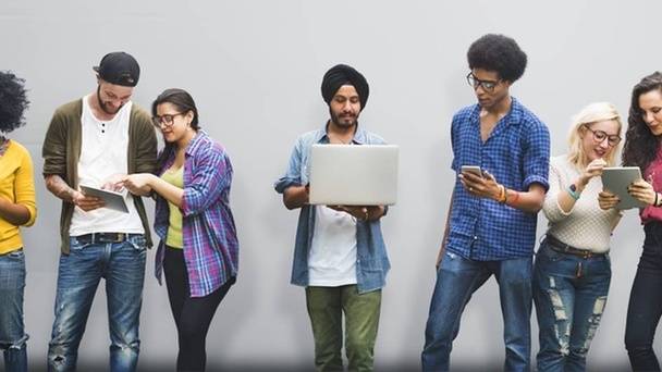 Group of young adults looking at cell phones and laptops